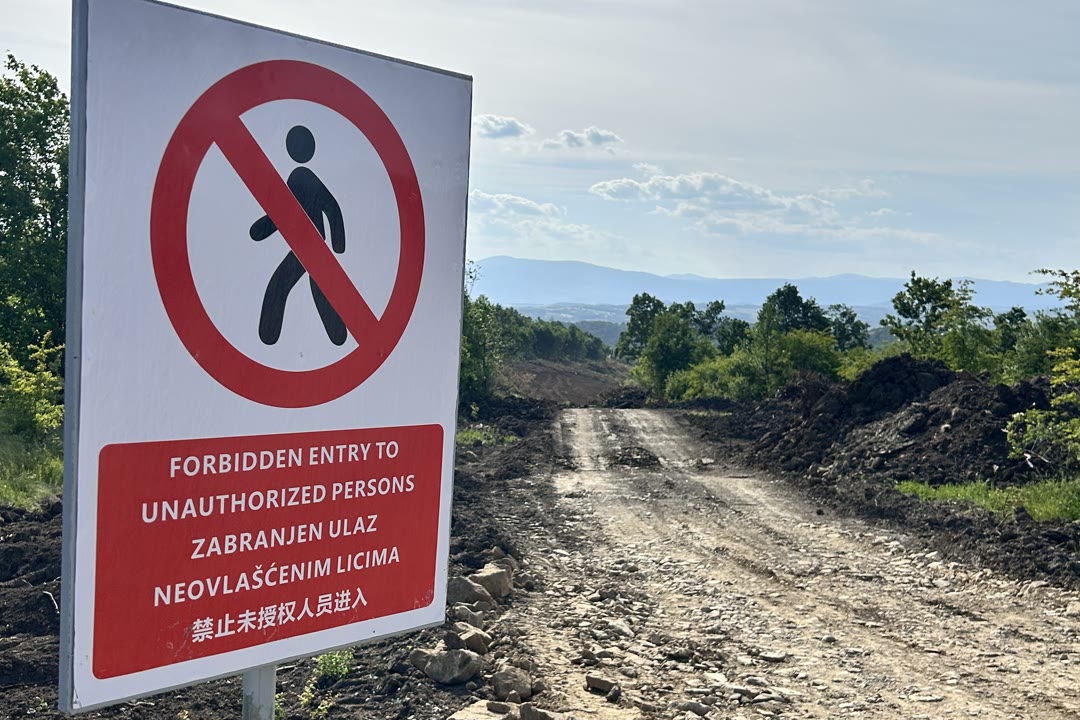 Tabla sa natpisom o zabrani ulaza neovlašćenim licima, pored sveže probijenog puta koji vodi preko brda.