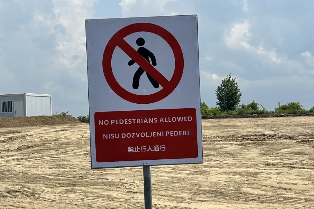 Trojezična tabla o zabrani pristupa na raščišćenom terenu. Na engleskom i kineskom piše da je pristup zabranjen pešacima, dok je u srpskom redu homofobna uvreda.